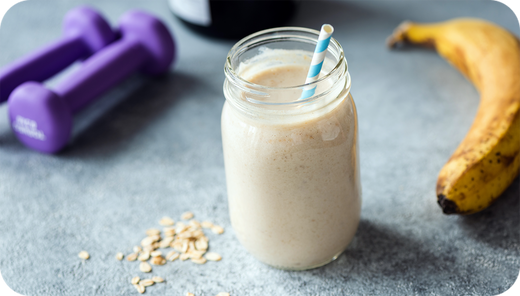 Chocolate Banana Coffee Shake with banana and dumbbells in background.