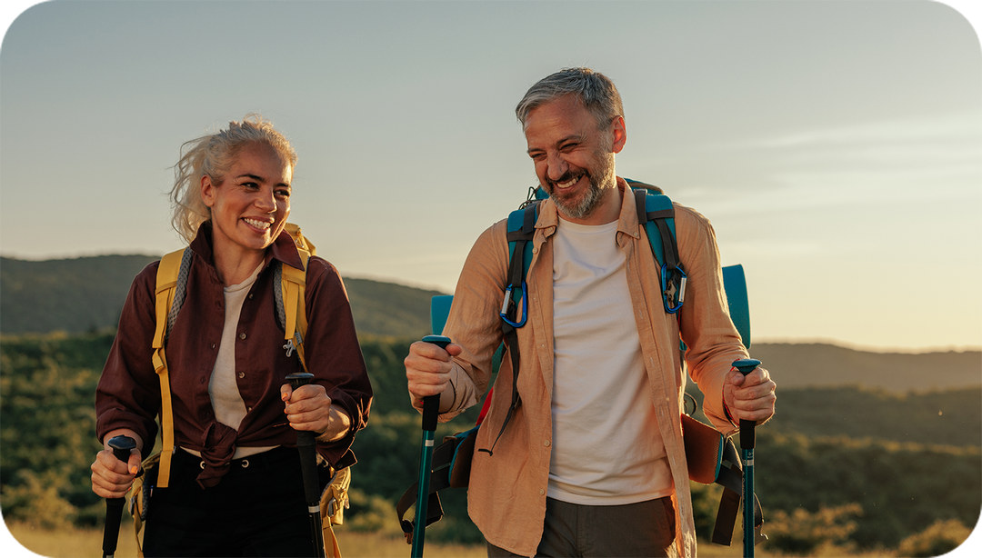 Middle-aged couple with walking sticks hiking.