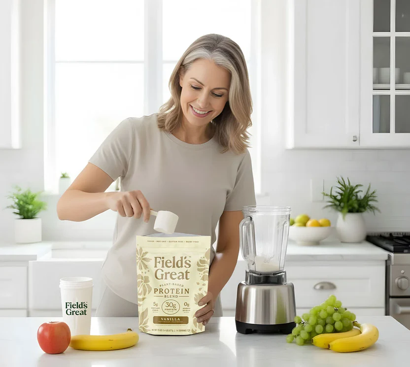 Woman in a kitchen preparing a smoothie with Field's Great protein powder.